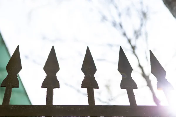 sharp metal spikes at the top of the fence in the background defocused sky
