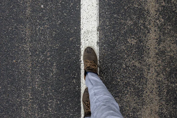 Μπότες του ταξιδιώτη που στέκεται στο πεζοδρόμιο στη διαχωριστική λωρίδα. — Φωτογραφία Αρχείου