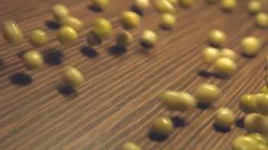 Kahverengi ahşap arka plan üzerinde konserve yeşil bezelye. 2 tekila. Ağır çekim. Yatay pan. Yakın-up.1. konserve yeşil bezelye haddeleme aşağı (soldan sağa) üzerinde kahverengi ahşap background.2. Yatay (soldan sağa) panorama.