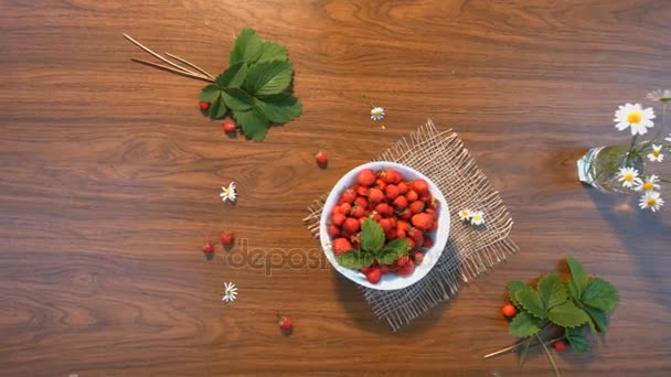 Strawberries and a bouquet of chamomiles on the table. Top view. — Stock Video