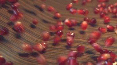 Kahverengi ahşap zemin üzerine nar taneleri. 2 tekila. Ağır çekim. 