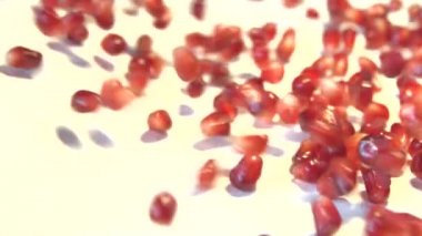 Beyaz zemin üzerine nar taneleri. 2 tekila. Ağır çekim.