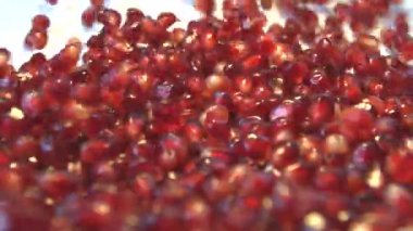 Beyaz zemin üzerine nar taneleri. 2 tekila. Ağır çekim. Dikey pan. Yakın çekim.