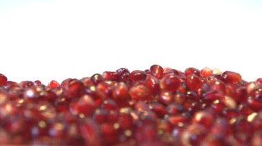 Beyaz zemin üzerine nar taneleri. 2 tekila. Ağır çekim. Yatay pan. Yakın çekim.