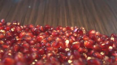 Kahverengi ahşap zemin üzerine nar taneleri. 2 tekila. Ağır çekim. Yatay pan. Yakın çekim.