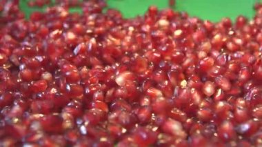 Yeşil bir arka plan üzerine nar taneleri. 2 tekila. Ağır çekim. Yatay pan. Yakın çekim.