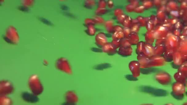 Granátové jablko zrna na zeleném pozadí. 2 výstřely. Zpomalený pohyb. — Stock video