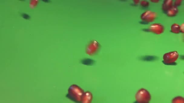 Granatapfelkörner auf grünem Hintergrund. 2 Schüsse. Zeitlupe. — Stockvideo