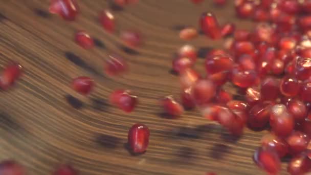 Pomegranate grains on a brown wooden background. 2 Shots. Slow motion. — Stock Video