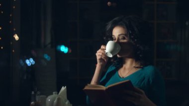 Sevimli kadın bir kafede. Ağır çekim. Güzel bir kadın cam arkasında bir kafede oturan ve bir kitap okuma. Çay ya da kahve içiyor. Kentsel ulaşım ve trafik cam yansıtır.