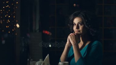 Sevimli kadın bir kafede. Ağır çekim. Güzel bir kadın cam ve rüyalar hakkında bir şey arkasında bir kafede oturuyor. Kentsel ulaşım ve trafik cam yansıtır.