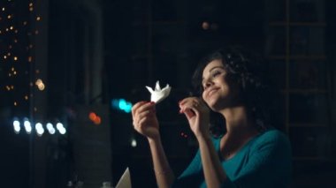 Sevimli kadın bir kafede. Ağır çekim. Güzel bir kadın rüyalar ve cam arkasında bir kafede oturuyor. Kağıt tekne ve gülümsüyor görünüyor. Kentsel ulaşım ve trafik cam yansıtır.