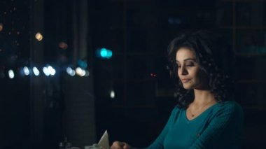 Sevimli kadın bir kafede. Ağır çekim. Güzel bir kadın cam ve rüyalar hakkında bir şey arkasında bir kafede oturuyor. Kentsel ulaşım ve trafik cam yansıtır.