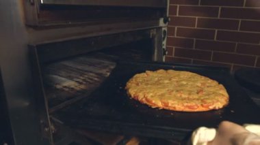 Pizza yemek. Ağır çekim. Eller pizza fırından alın ve kesme tahtası için transfer. Pişmiş pizza tahta üzerinde döner.