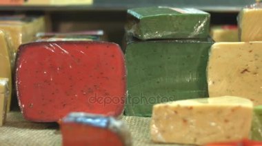 Peynir süpermarkette rafta. Yatay (soldan sağa) pan. Elini bir raf yeşil peynir parçası alır.