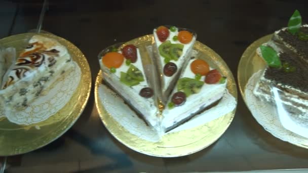 多種多様なケーキ 平面図です カメラに沿って移動する 左から右へ 棚に横たわるさまざまな種類のケーキやペストリー — ストック動画