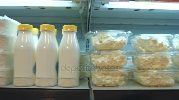 Savanyú tejtermékek a szupermarketben. Vízszintes pan. A kamera mozog a polcon, amelyben vannak olyan túró, tej, kefir és joghurt.