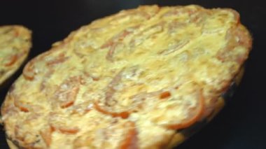 İki pizza döndürün. Yakın çekim. Yatay (sağdan sola) pan. Karanlık bir arka plan üzerinde kurullarında pizzalar döndürmek.