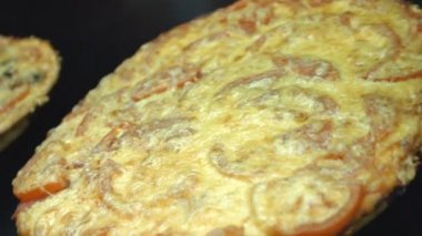 İki pizza döndürün. Yakın çekim. Yatay (sağdan sola) pan. Karanlık bir arka plan üzerinde kurullarında pizzalar döndürmek.