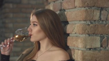 Güzel bir kız şarap içiyor. 2 tekila. Yavaş motion.1. Yakın çekim. Yatay pan. Kız eski tuğla duvara yakın duruyor ve şampanya veya beyaz wine.2 içiyor. Güzel bir kız beyaz şarap veya şampanya içinde eski bir şarap mahzeni tatma.