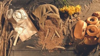 Tatlı ekmek buğday unu ile yapılan. Ağır çekim. Adamın elleri tablo büyük bir çörek al ve ikiye böl. Kamera olduğunuz buğday kulaklar, un, tahıl, çeşitli çörekler ve yulaf bir demet bir çanta bir eski ahşap masa üzerinde hareket eder..