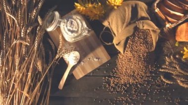 Ekmek, buğday, un ve çiçekler ile natürmort. Üstten Görünüm. Yatay (soldan sağa) pan. Buğday, un ile banka kulaklar, tahıl ve ekmek bir çanta üzerinde eski bir ahşap masa vardır.