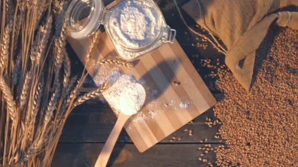 小麦の粉で作った甘いパンします 平面図です クローズ アップ カメラがいる小麦の耳 小麦粉 穀物の袋 各種パン 古い木製のテーブルの上に移動します — ストック動画