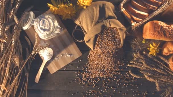 小麦粉 花のある静物 平面図です 左から右に 水平パンします 小麦粉と銀行の耳 穀物やパンの袋 古い木製のテーブル — ストック動画