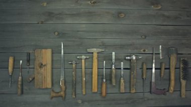 Eski el aletleri. Üst manzara. Eller masadan küçük bir çekiç ve keski alır. Masanın üzerinde tahta saplı eski aletler bulunur: tornavida, keski, el testeresi, çekiç, balta, avlu, metal fırça, eklemli..