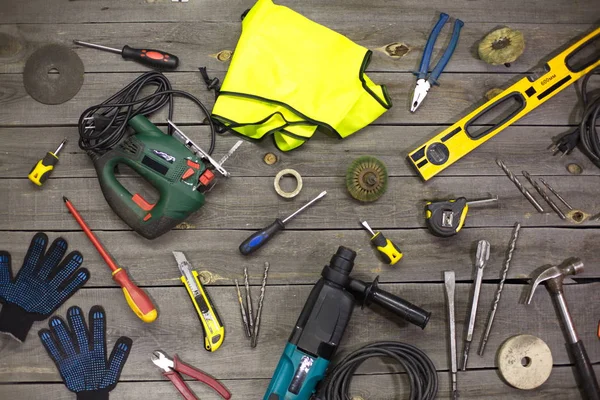 A variety of electro and hand tools and special clothing. Top view.On the table are tools for various types of construction and repair work on wood, metal, concrete, plastic and other materials.
