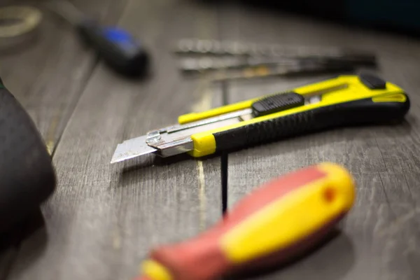 Tools on the table.On the table is: a knife for paper, a screwdriver ( in no focus ) and a drills on concrete ( in no focus ).