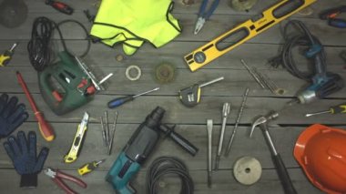Çeşitli elektro, el aletleri ve özel giysiler. En iyi görüntü. Masanın üzerinde ahşap, metal, beton, plastik ve diğer malzemeler üzerinde çeşitli inşaat ve onarım işleri için aletler bulunuyor. Kamera soldan sağa hareket ediyor..