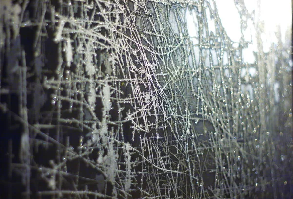 Camdaki soyut desenler. Donmuş pencereler karanlıktaki ışıkla dışarıdan aydınlatılmış..