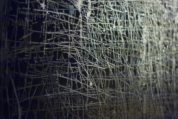 Camdaki soyut desenler. Donmuş pencereler karanlıktaki ışıkla dışarıdan aydınlatılmış..