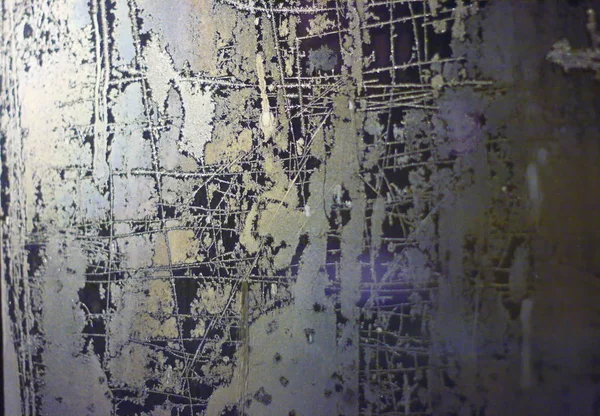 Camdaki soyut desenler. Donmuş pencereler karanlıktaki ışıkla dışarıdan aydınlatılmış..