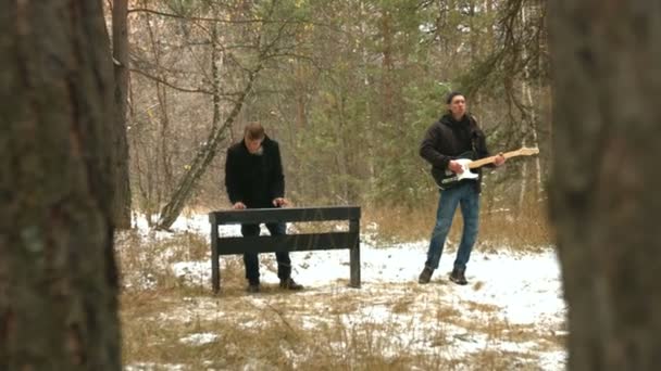 森の中のミュージシャン 冬の森で二人で音楽を演奏する 一方はデジタル フォルテピアーノとダンス もう一方はエレキ ギターを歌い演奏する — ストック動画