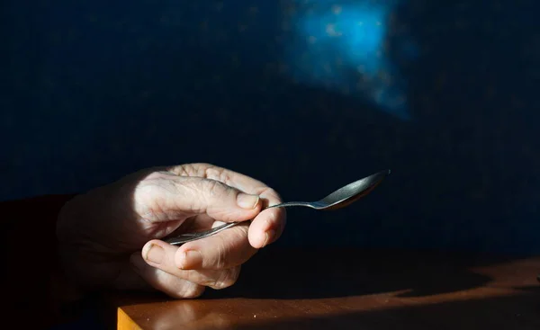 Elinde bir çay kaşığı. Büyükannenin eli kaşığı tutuyor. Yakın plan..
