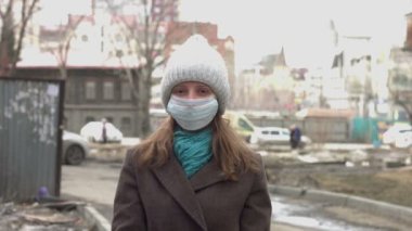 Tıbbi maskeli bir kadın. Şehir caddesinde bir kadının portresi. Koruyucu tıbbi maskesini çıkarıyor..