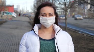 Tıbbi maskeli bir kız. Şehir caddesinde bir kızın portresi. Koruyucu tıbbi maskesini çıkarıyor..