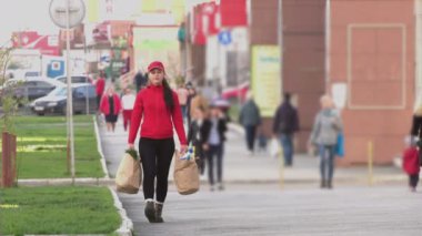 Kurye (ya da bir ev hanımı, bir aşçı) sokakta yiyecek paketleri ile birlikte. Yemek dağıtım servisinden bir kız sokakta yürüyor, ellerinde yiyecek paketleri taşıyor..
