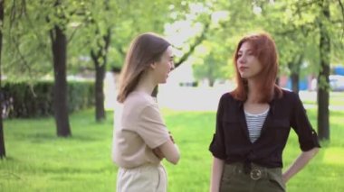 Parkta iki kız var. Ağır çekim. İki kız ağaçların arasında yeşil bir sokakta dikiliyorlar ve konuşarak eğleniyorlar. Rüzgar saçlarını savurur.