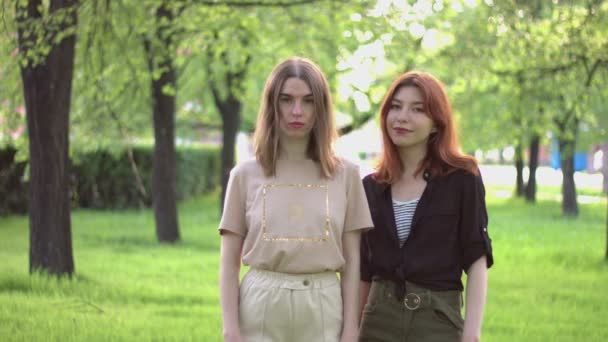 公園の２人の女の子 スローモーション2倍 春の公園 二人の女の子が木の間の緑の路地に立っているとカメラを見て — ストック動画