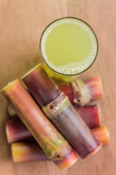 Jugo de caña de azúcar con trozo de caña de azúcar sobre fondo de madera. Para — Foto de Stock