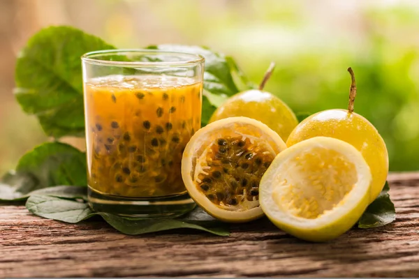 Fruta de la pasión - Mitad de frutas de la pasión y jugo con hojas en el fondo de madera vintage. Primer plano, Seleccionar enfoque . — Foto de Stock