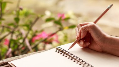 Ellerini kızın yazma - el yeşil doğa arka plan ile eski ahşap doku ile defter ve çöl gülü ayakta bir kurşun kalemle yazma kızın. Portre, Select odak. g 