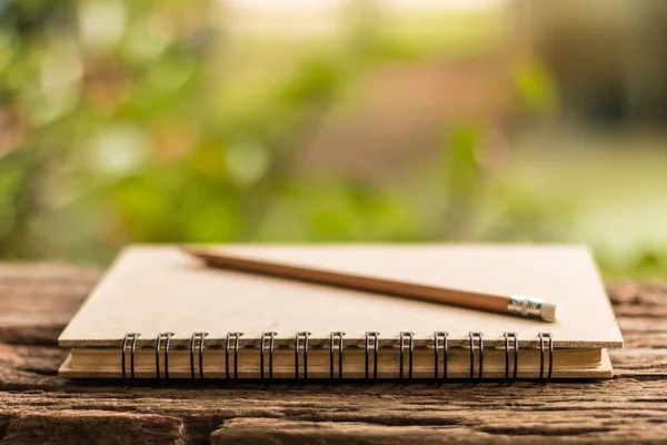 Journal marron - Journal marron et crayon sur table en bois vintage nature morte avec fond vert nature. Gros plan, Sélectionner la mise au point . — Photo