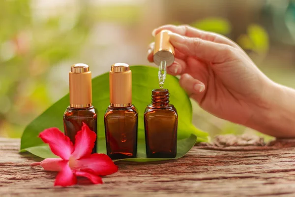 Hand holding a pipette serum with three Spa cosmetics container