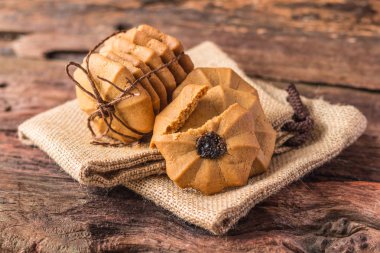 Çerezler - kahverengi kumaş arka plan üzerinde kahverengi iple bağlı çikolatalı kurabiye yığını.