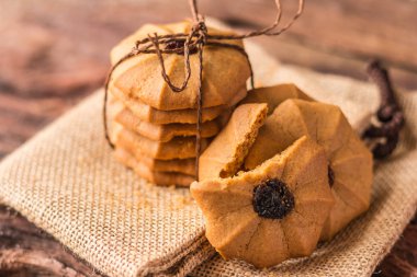 Çerezler - kahverengi kumaş arka plan üzerinde kahverengi iple bağlı çikolatalı kurabiye yığını.