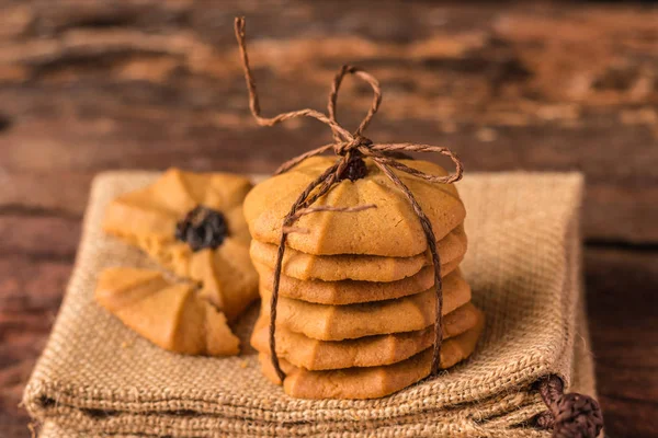 Galletas - Galletas de chispas de chocolate apiladas con cuerda marrón en el fondo de la servilleta hessiana . —  Fotos de Stock